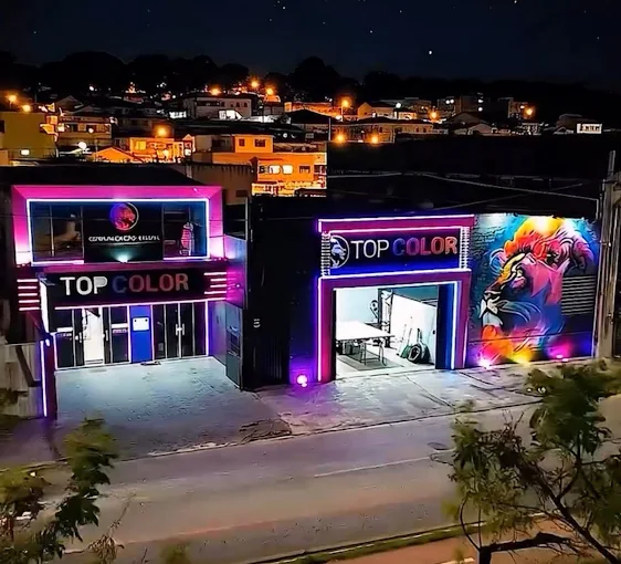 Fachada da Gráfica Top Color iluminada à noite, com o leão grafitado na parede